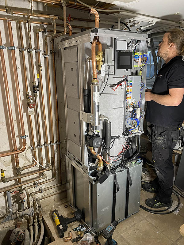 Montör från EkoEnergi installerar värmepump i källare i Skåne